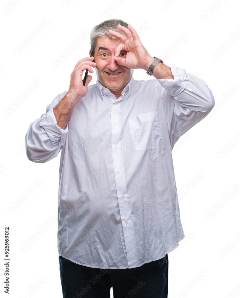 Handsome senior man talking on smartphone over isolated background with happy face smiling doing ok sign with hand on eye looking through fingers Handsome senior man talking on smartphone over isolated background with happy face smiling doing ok sign with hand on eye looking through fingers