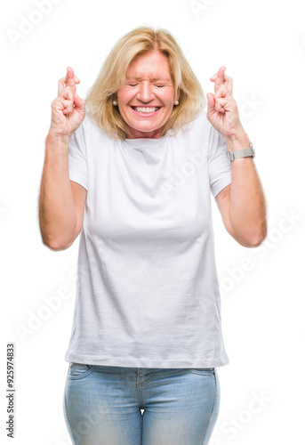 Middle age blonde woman over isolated background smiling crossing fingers with hope and eyes closed. Luck and superstitious concept.