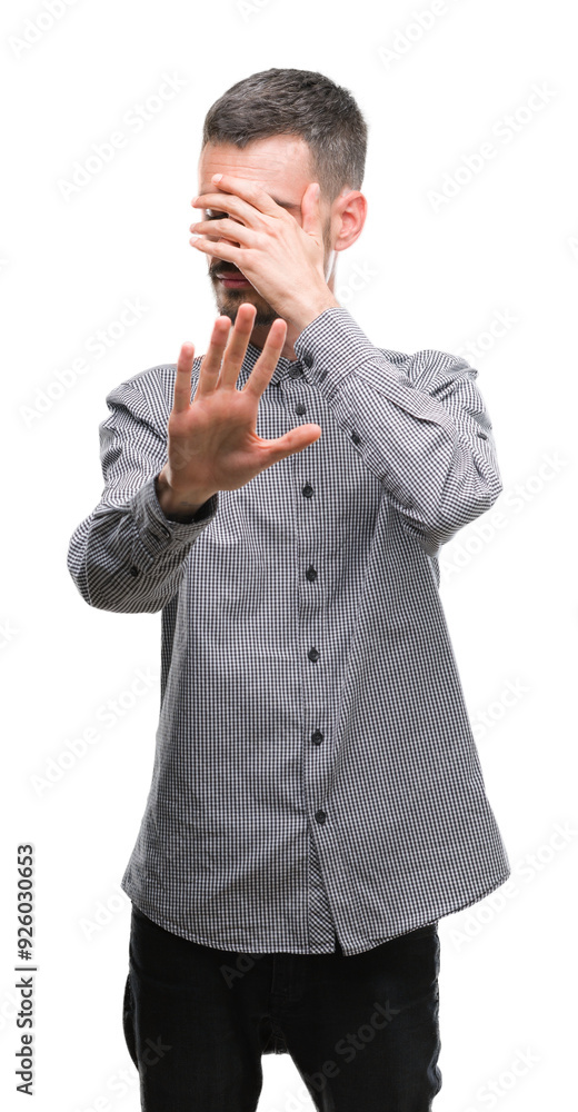 Young hipster man covering eyes with hands and doing stop gesture with sad and fear expression. Embarrassed and negative concept. Young hipster man covering eyes with hands and doing stop gesture with sad and fear expression. Embarrassed and negative concept.