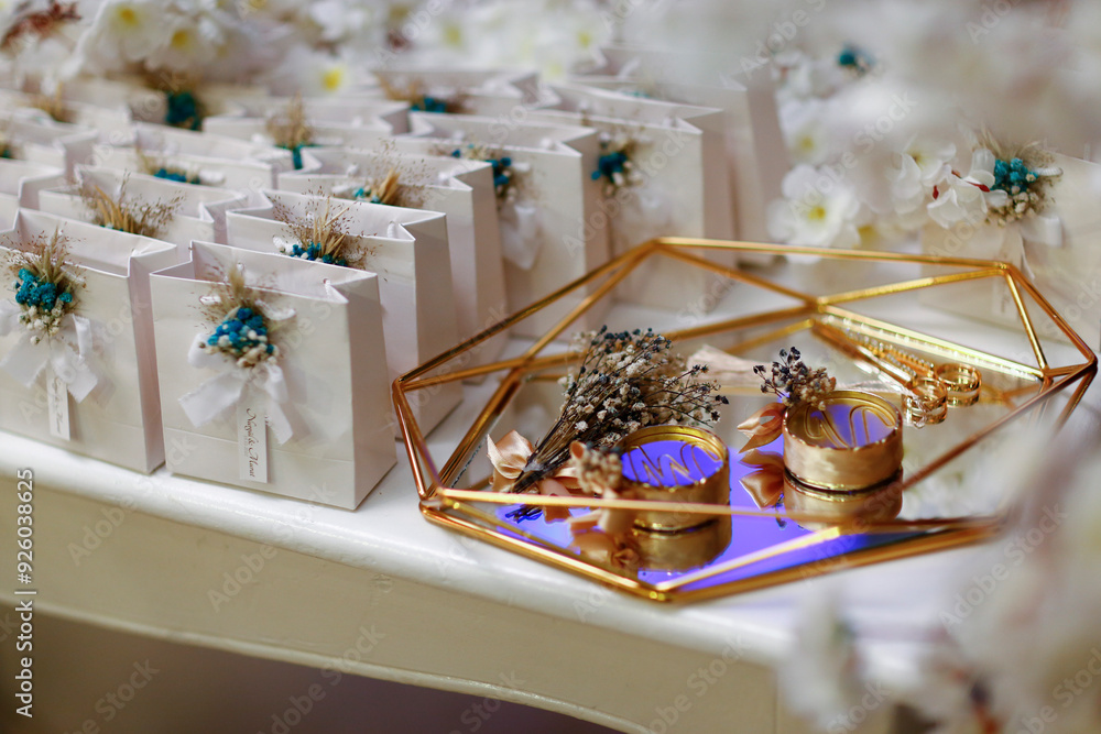 Elegant wedding favor boxes with gold accents and dried flowers, displayed on a geometric glass tray