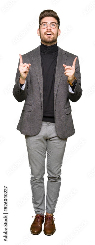 Young handsome business man wearing glasses amazed and surprised looking up and pointing with fingers and raised arms. Young handsome business man wearing glasses amazed and surprised looking up and pointing with fingers and raised arms.