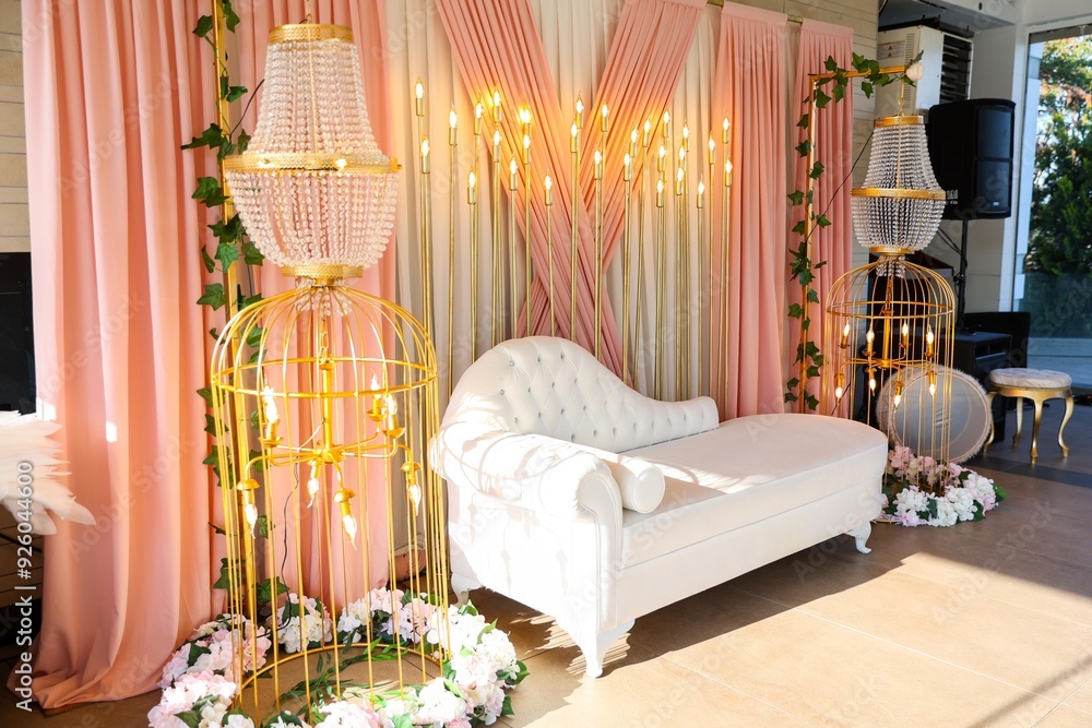 Elegant wedding ceremony setup with a floral arch, a crystal chandelier, and a soft pink backdrop