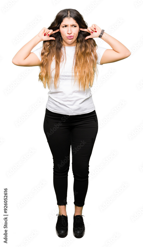 Young beautiful woman wearing casual white t-shirt covering ears with fingers with annoyed expression for the noise of loud music. Deaf concept. Young beautiful woman wearing casual white t-shirt covering ears with fingers with annoyed expression for the noise of loud music. Deaf concept.