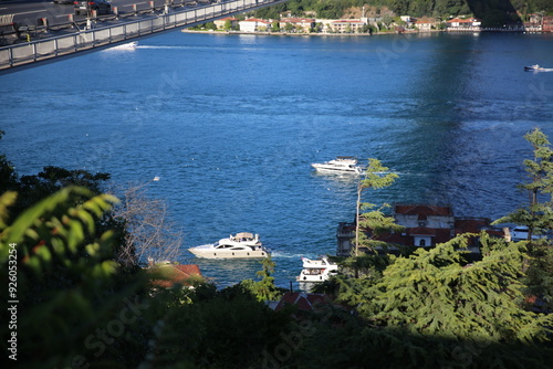 Obraz na płótnie A breathtaking view of the Bosphorus with boats sailing past a historic bridge and lush greenery w salonie