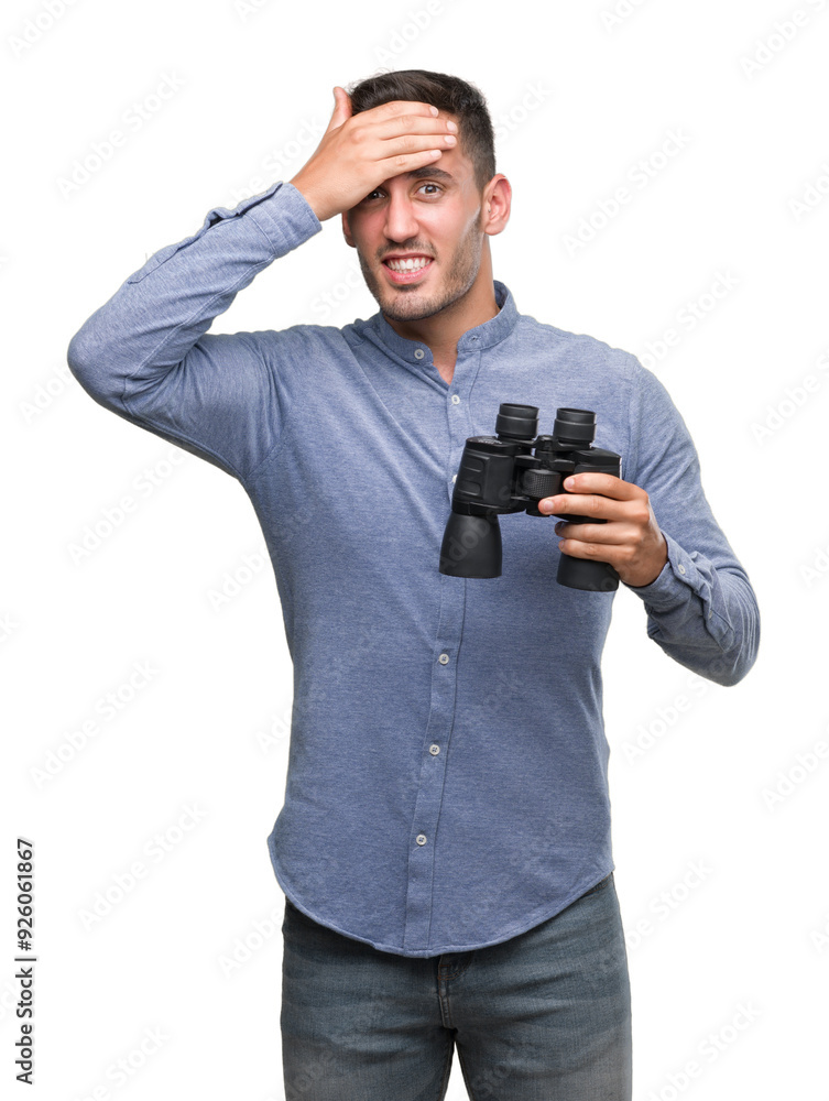 Handsome young man looking through binoculars stressed with hand on head, shocked with shame and surprise face, angry and frustrated. Fear and upset for mistake. Handsome young man looking through binoculars stressed with hand on head, shocked with shame and surprise face, angry and frustrated. Fear and upset for mistake.