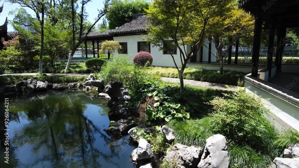 A serene public traditional Chinese garden with a water pond ...