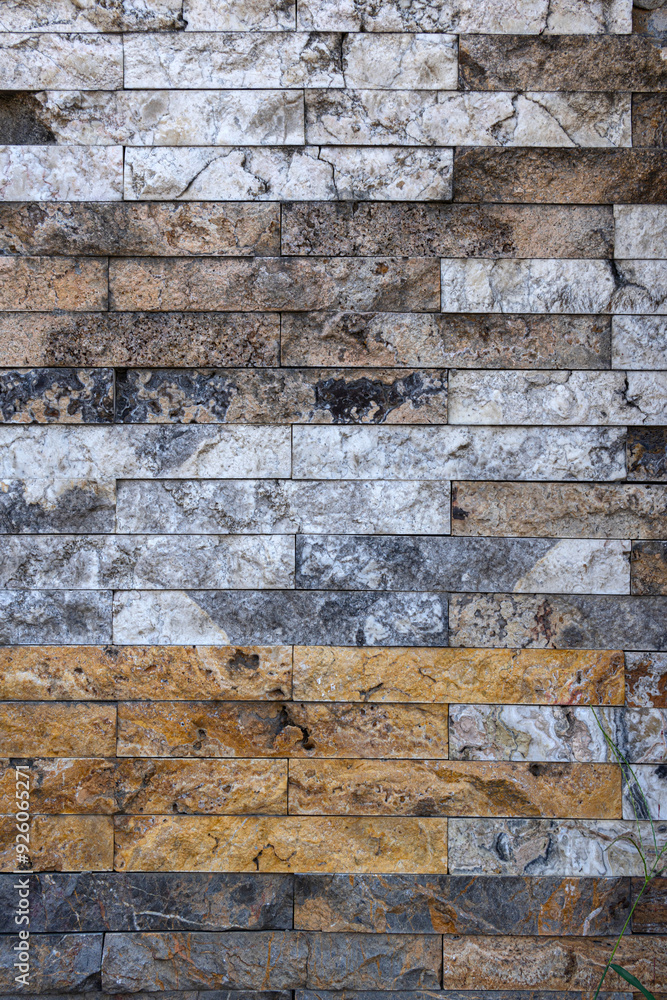 A wall made of brown and white stones. The wall is old and has a weathered appearance. A wall made of brown and white stones. The wall is old and has a weathered appearance.