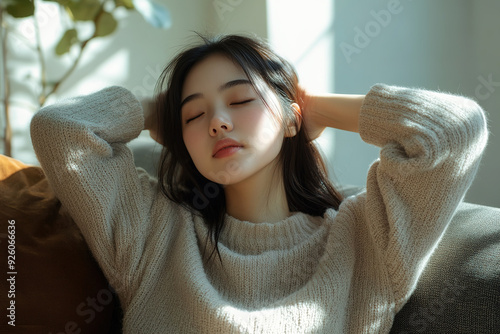 Calm Asian woman resting on a sofa at home, with hands behind her head and eyes closed, wearing casual clothes, in a serene living room environment, captured with a wide-angle lens in a hyper-realisti