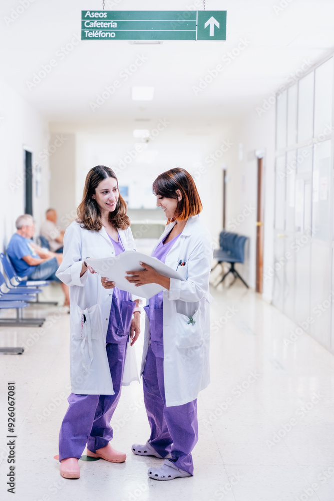 Two young happy female doctors working together in a hospital