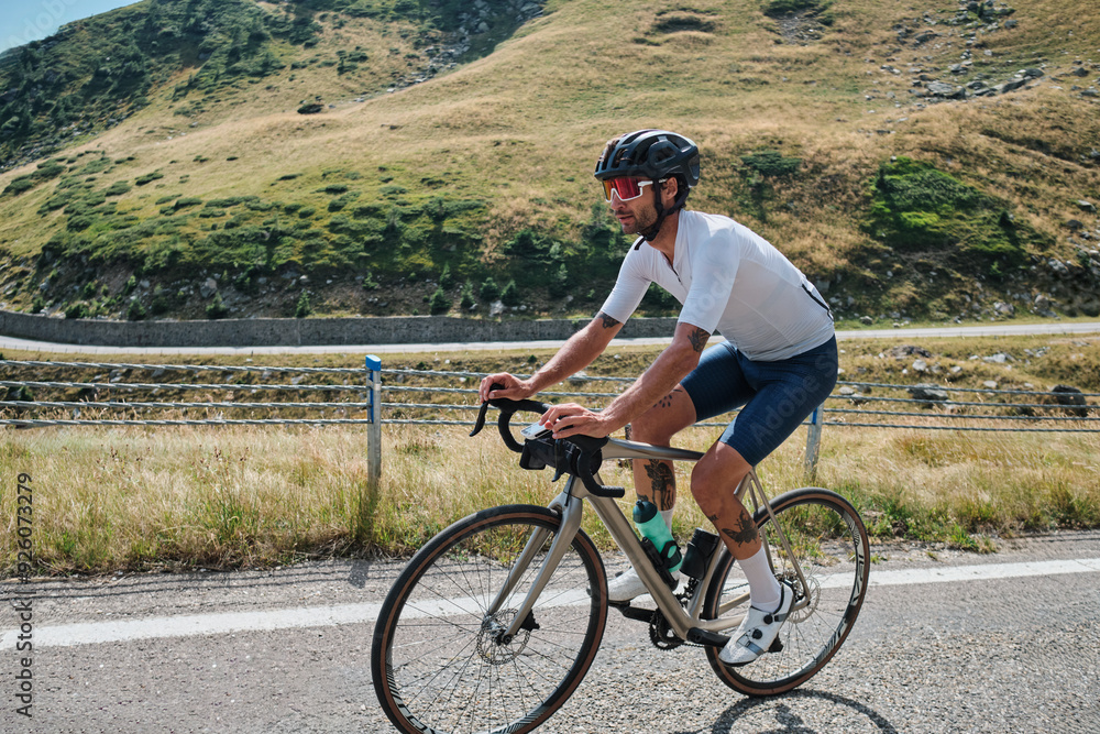 Male cyclist during ride a bicycle. Sports motivation image.Good road for cycling. Man cyclist riding a gravel bike with a view of the mountains. Travel biking concept. Transfăgărășan road in Romania. Male cyclist during ride a bicycle. Sports motivation image.Good road for cycling. Man cyclist riding a gravel bike with a view of the mountains. Travel biking concept. Transfăgărășan road in Romania.