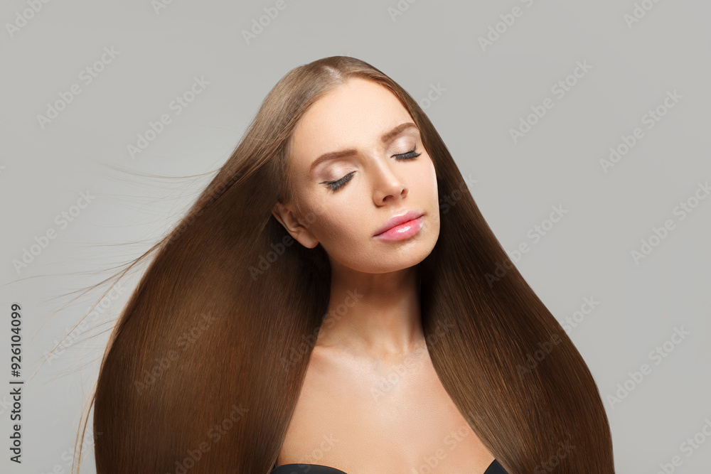 Glamorous woman face. Model with long brown hair and make-up on grey background. Beauty, hair care and cosmetic portrait Glamorous woman face. Model with long brown hair and make-up on grey background. Beauty, hair care and cosmetic portrait