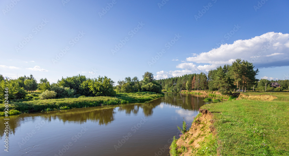 A river with a green forest on the left bank A river with a green forest on the left bank