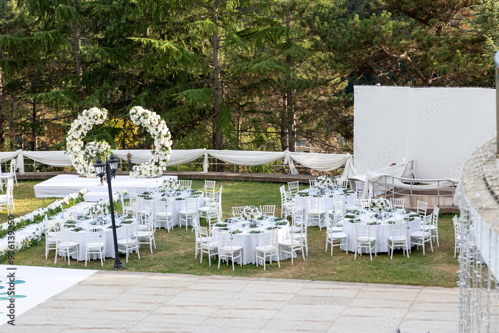 Elegant outdoor wedding venue with white decor and floral arch