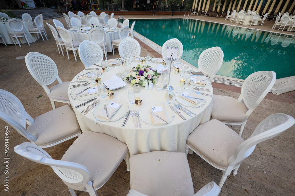 Elegant Poolside Wedding Reception with Round Tables and White Chairs
