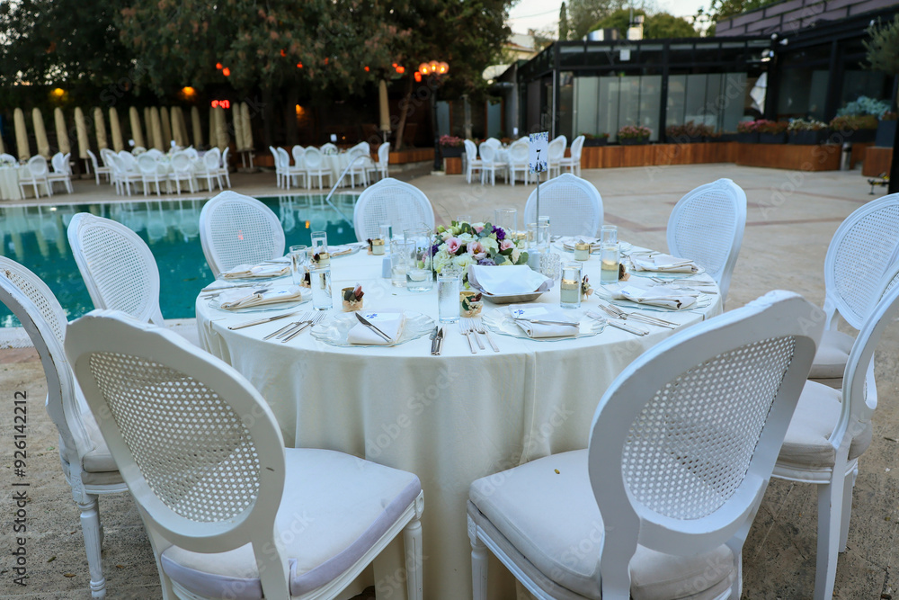 Elegant Poolside Wedding Reception with Round Tables and White Chairs