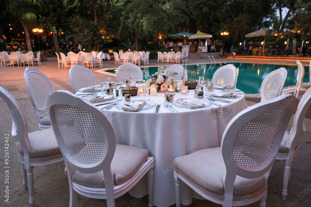 Outdoor Wedding Setup: Round Tables and Floral Decor by a Swimming Pool
