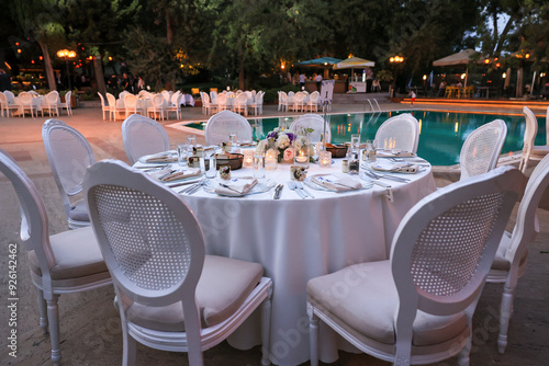 Outdoor Wedding Setup: Round Tables and Floral Decor by a Swimming Pool