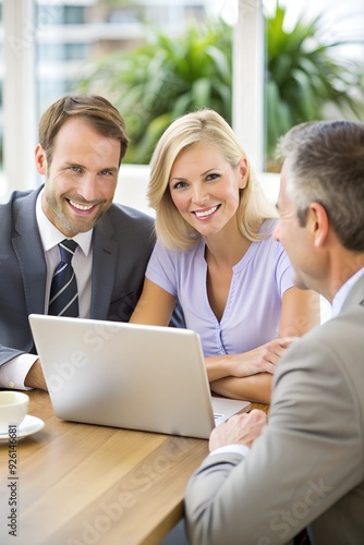 Happy couple using laptop with their insurance agent during a meeting.