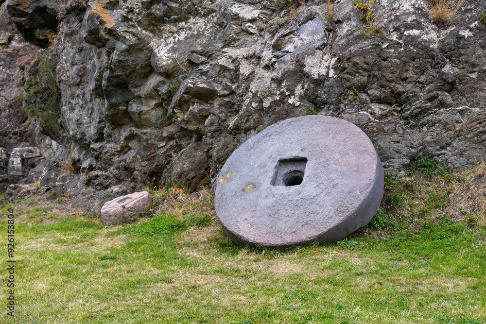 Ancient Stone Wheel and Smaller Artifact Beside Rocky Outcrop in Historical Site Ancient Stone Wheel and Smaller Artifact Beside Rocky Outcrop in Historical Site