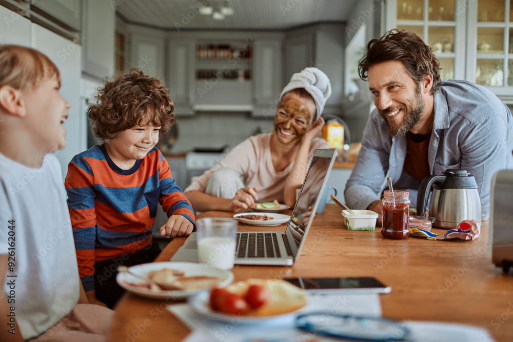 Happy family enjoying breakfast together in modern kitchen with laptop Happy family enjoying breakfast together in modern kitchen with laptop