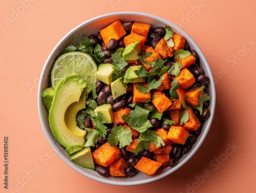 A vibrant bowl of sweet potatoes, black beans, avocado, and lime, garnished with cilantro.