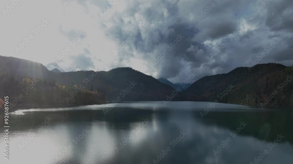 Panoramic view of the Alpsee lake in Autumn trees season and Bavaria Alps in background, beautiful reflections in water Panoramic view of the Alpsee lake in Autumn trees season and Bavaria Alps in background, beautiful reflections in water