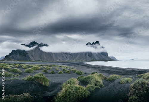 Episches Wetter an schwarzem Sandstrand mit kantigen Bergen und steilen Klippen zum Meer photo