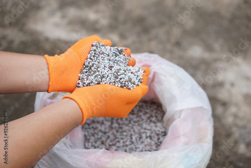 Close up hands hold mixed chemical fertilizer. Concept; chemical fertilizer production use in agriculture consists of basic nutrients which are Nitrogen (AND), Phosphate (P2O5) and Potassium (K2O).   