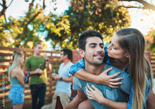 Couple, hug and fun backyard with friends, love and outdoor at labor day party and social event. Beer, conversation and happy people with summer, vacation and group reunion with smile and care