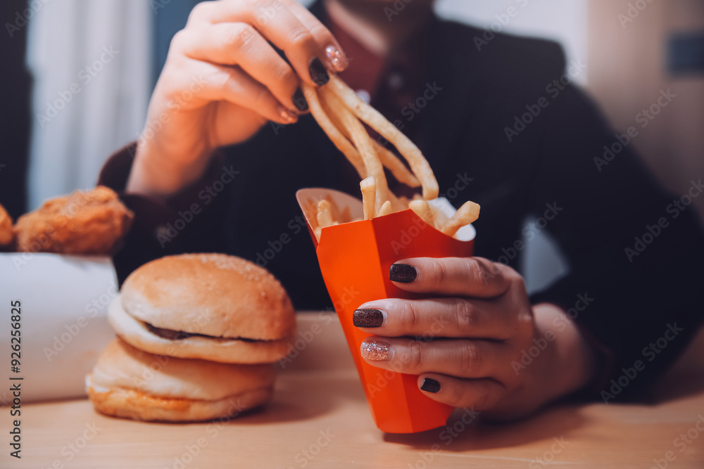 Asian woman holding french fries and eating happily in restaurant Asian woman holding french fries and eating happily in restaurant
