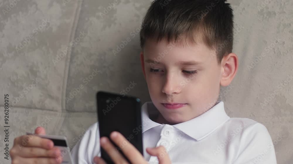 teenager shopping online, caucasian boy 11 years old shopping online sitting on couch at home holding bank card and phone teenager shopping online, caucasian boy 11 years old shopping online sitting on couch at home holding bank card and phone