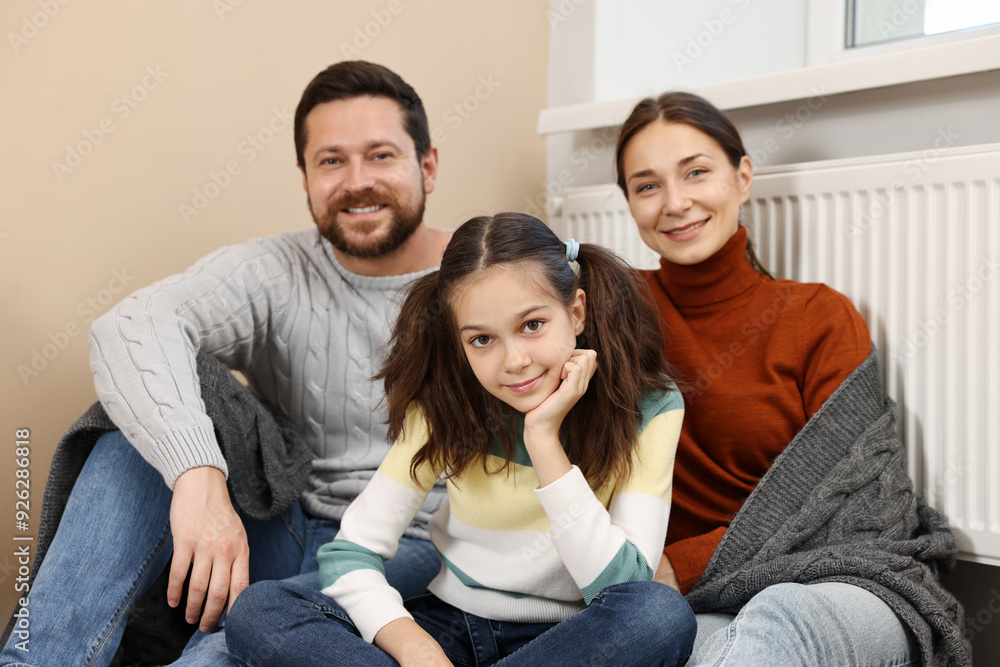 Happy family near heating radiator at home Happy family near heating radiator at home