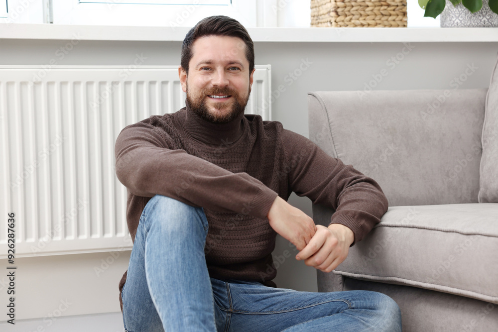 Happy man near heating radiator at home Happy man near heating radiator at home