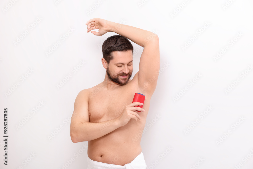 Obraz premium Handsome man applying solid deodorant on white background