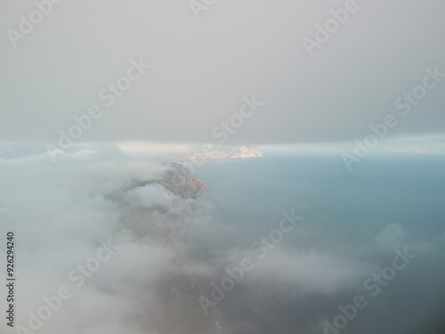 Aerial view. Blue sky sun and fog over calm sea. The drone flies over foggy and fluffy clouds. Abstract aerial nature summer ocean sunset sea and sky background. Vacation, travel and holiday concept.