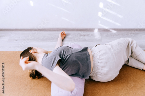 Canvas Print Woman in casual clothing practicing yin yoga pose reclined twist on bolster