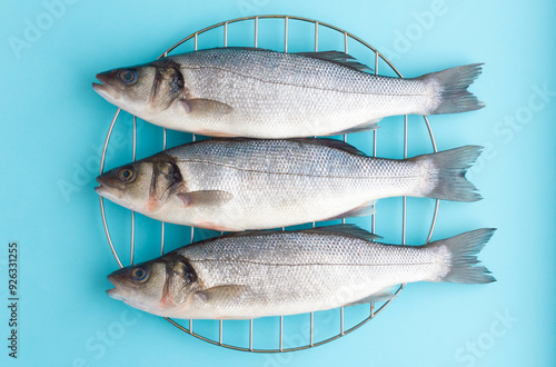 Three fresh sea bass on the grill on a blue background. Natural sea fish, healthy nutrition, Mediterranean diet.