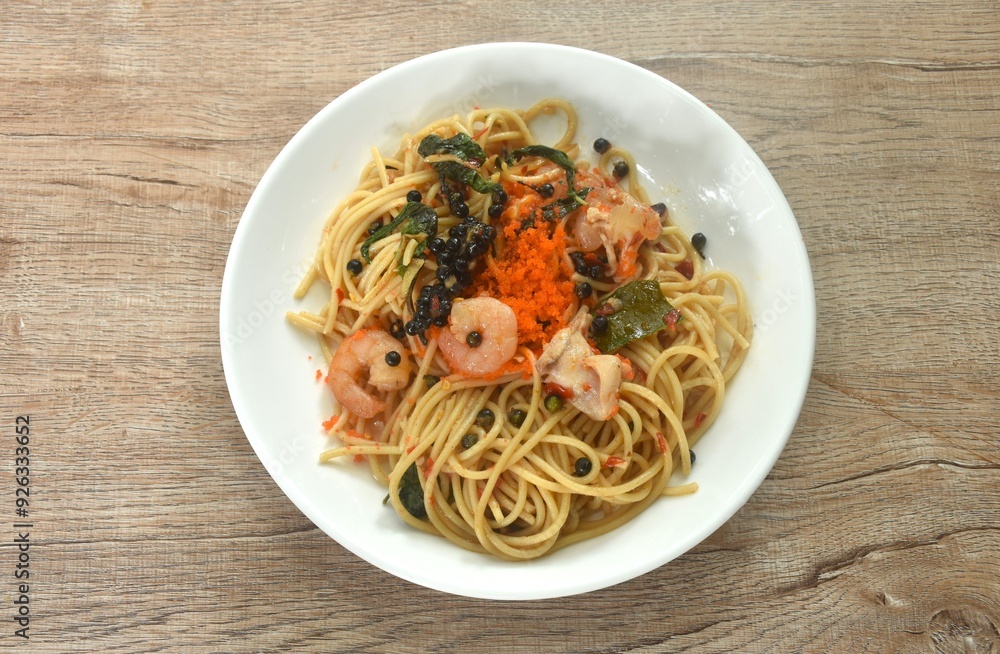 spicy stir fried spaghetti slice squid and shrimp with chili and basil leaf topping shrimp egg in sauce on plate spicy stir fried spaghetti slice squid and shrimp with chili and basil leaf topping shrimp egg in sauce on plate