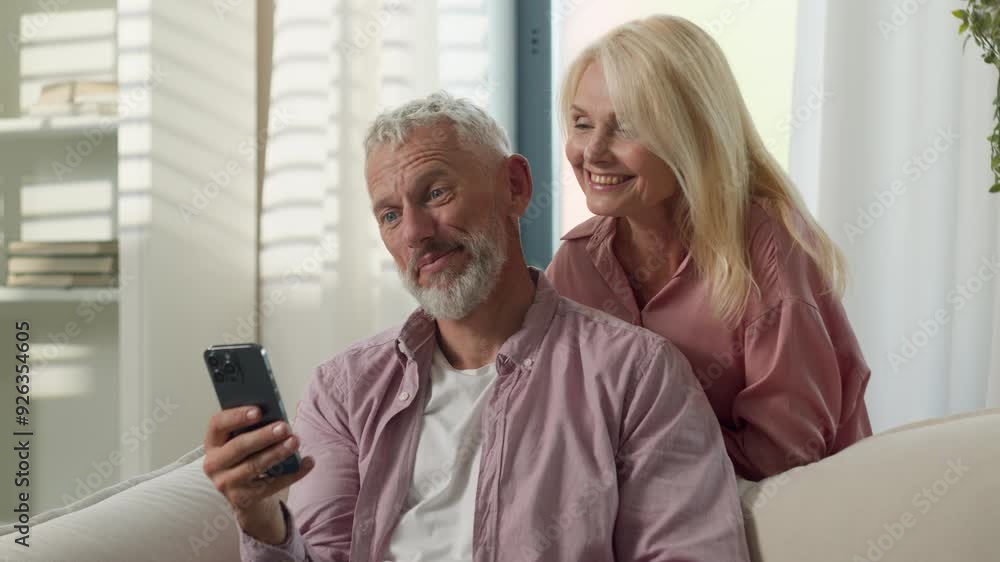 Cheerful Caucasian old senior elderly couple family talking mobile phone gadget man male woman female online video call wife husband talk blogging vlog together waving hands greeting inside home room Cheerful Caucasian old senior elderly couple family talking mobile phone gadget man male woman female online video call wife husband talk blogging vlog together waving hands greeting inside home room