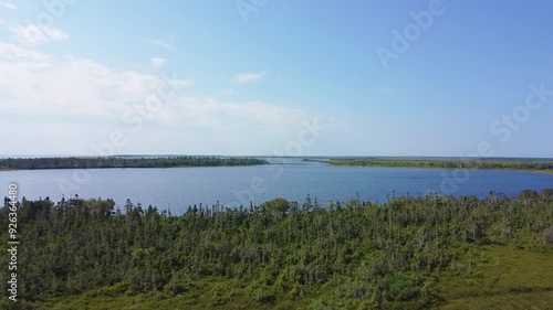 Drone en rotation sur les berges de La queue de Mal Baie (Mal Bay) & du Golfe St-Laurent, Ile Miscou, Nouveau-Brunswick. Vue aérienne de la tourbière & la bordure de conifères bordant les eaux bleues. photo