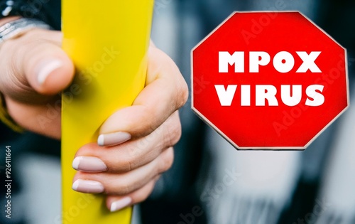 Hand gripping a yellow pole with mpox virus warning sign in a public transportation setting photo