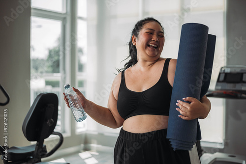 Plus size Asian woman exercises in gym. Beautiful overweight woman in sportswear smiling and happy in fitness. concept of body positive, self-acceptance, weight loss.