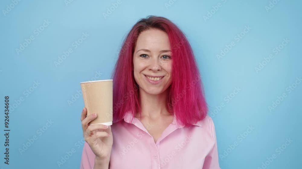 Woman with pink hair and take away coffee cup on blue background, drinking cappuccino to go, enjoying caffeine, feeling happy. Woman with pink hair and take away coffee cup on blue background, drinking cappuccino to go, enjoying caffeine, feeling happy.