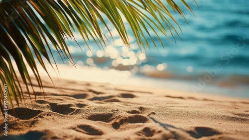 Sandy shore meets shimmering turquoise water under palm fronds. Sunlight creates magical bokeh on gentle waves. Perfect snapshot of a serene tropical getaway, inviting relaxation and escape.