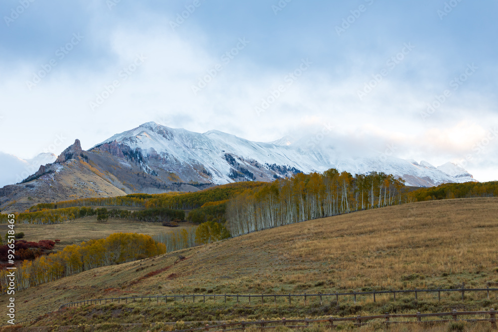 Fototapeta premium Hazy fall landscape in San Juan Mountains range, with fields and aspen in the foreground, Dolores County, Colorado, USA