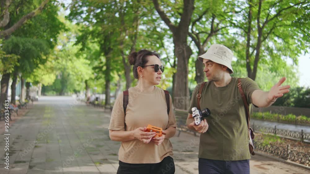 A cheerful couple of aged tourists in a Panama hat and sunglasses walks on a busy street on a sunny day, exploring the city and photographing the sights with a film camera A cheerful couple of aged tourists in a Panama hat and sunglasses walks on a busy street on a sunny day, exploring the city and photographing the sights with a film camera