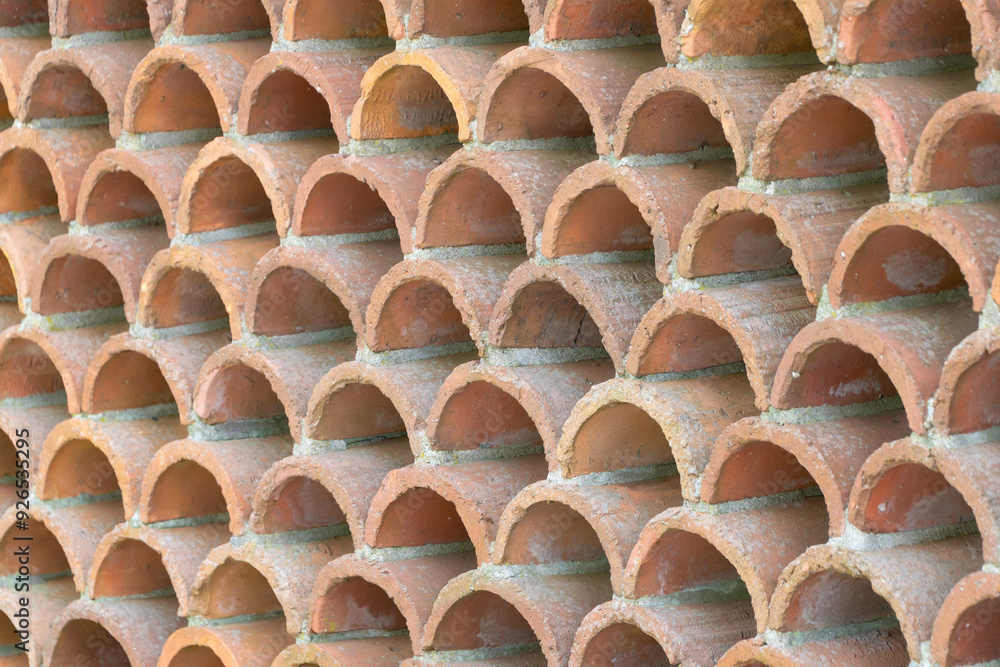 Obraz premium Decorative fence made of semicircular bricks, arranged in a staggered pattern, creating a unique design with gaps between the elements.