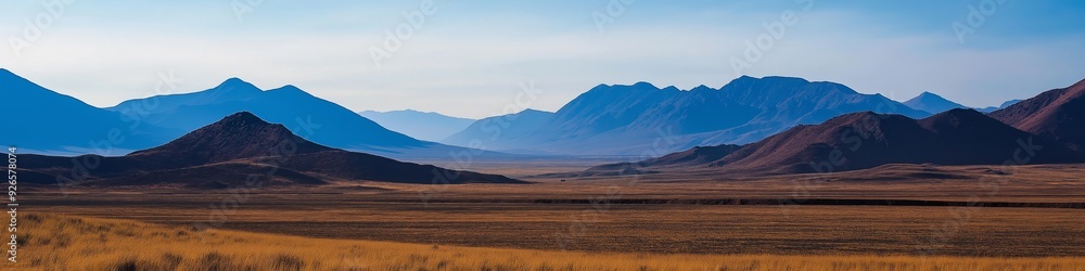 Obraz premium A mountain range with a clear blue sky in the background. The mountains are covered in trees and the sky is clear