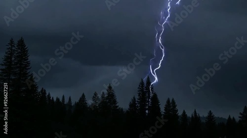 Thunderstorm with lightning strikes over a dense forest in the evening