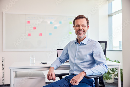 Relaxed businessman sitting in a chair with a smile in a bright office.